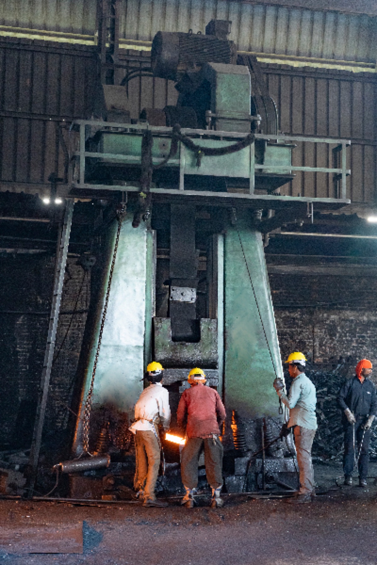 Workers handling a glowing hot forging billet at a 3-ton belt drop forging hammer