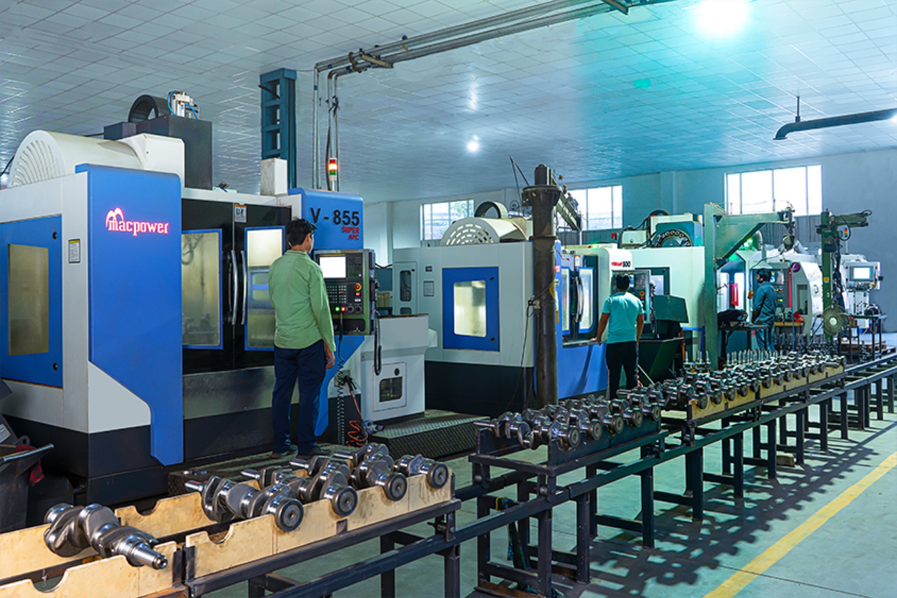 Vertical machining centres in line with operators and a long conveyor rack of machined crankshafts